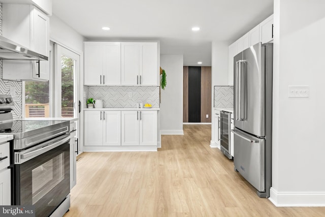 kitchen with wall chimney range hood, beverage cooler, appliances with stainless steel finishes, and tasteful backsplash