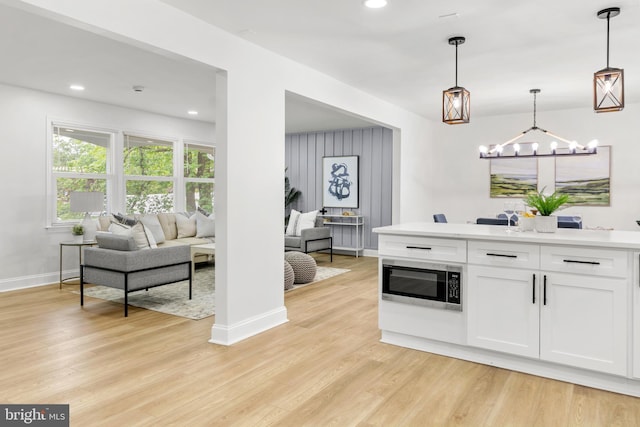 bar featuring light wood-style floors, pendant lighting, baseboards, and stainless steel microwave