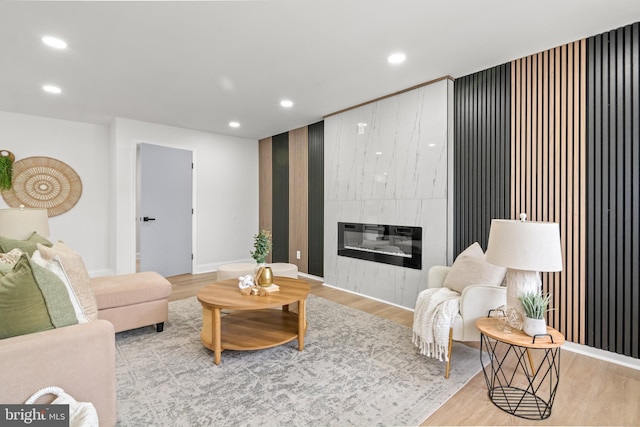 living area with recessed lighting, baseboards, wood finished floors, and a fireplace