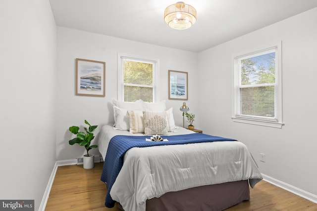 bedroom with baseboards, multiple windows, and wood finished floors