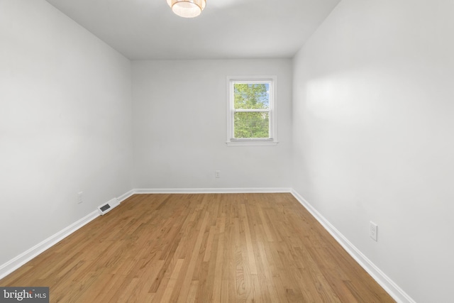 spare room featuring visible vents, light wood-style flooring, and baseboards
