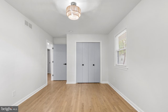 unfurnished bedroom featuring baseboards, visible vents, light wood-style flooring, and a closet