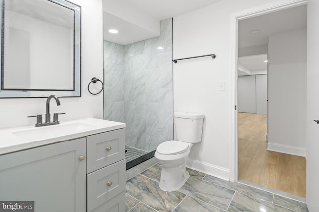 bathroom featuring vanity, baseboards, toilet, and tiled shower