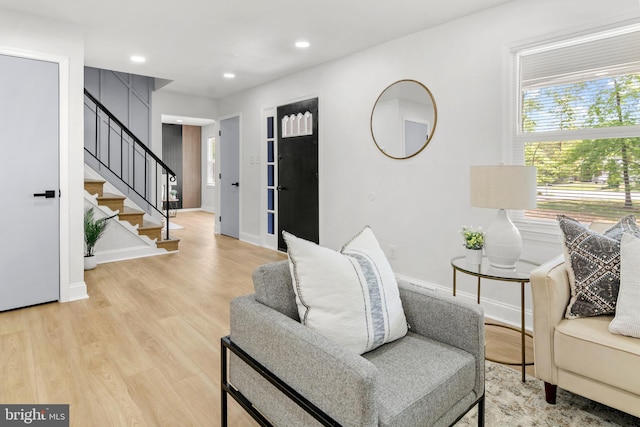living area featuring baseboards, recessed lighting, light wood finished floors, and stairway