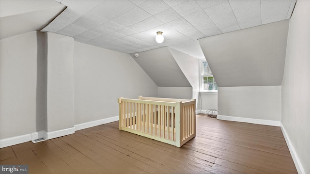additional living space featuring baseboards, wood-type flooring, and vaulted ceiling