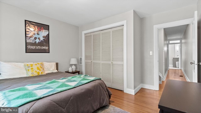 bedroom with a closet, light wood-style flooring, and baseboards