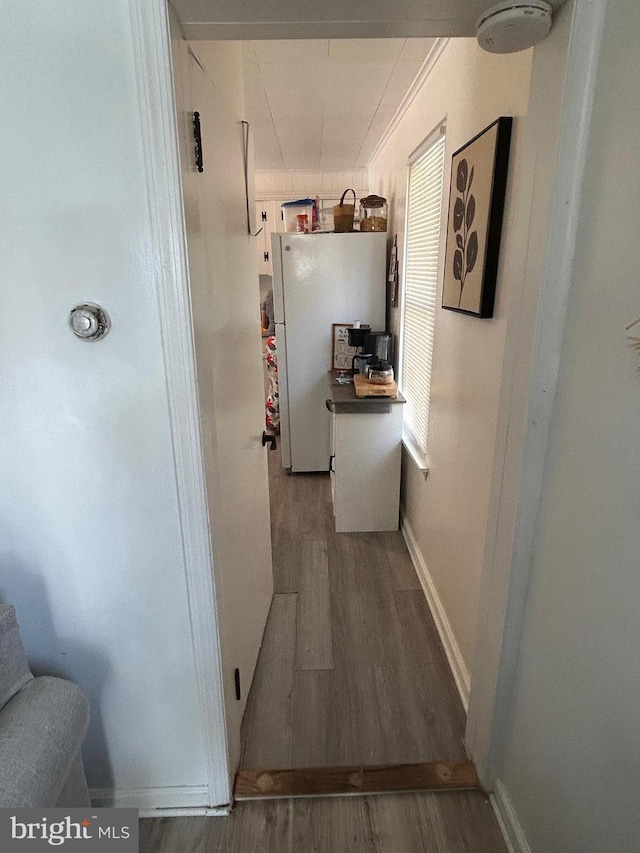 corridor featuring baseboards and wood finished floors