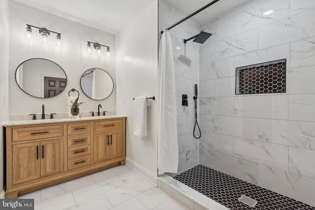 bathroom with double vanity, marble finish floor, baseboards, a sink, and a tile shower
