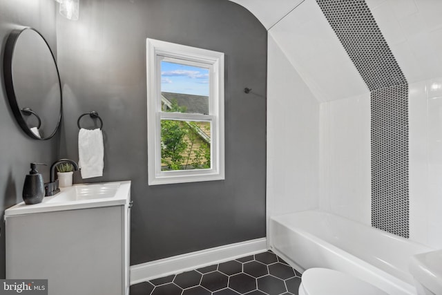 full bath with tile patterned flooring, vanity, toilet, baseboards, and washtub / shower combination