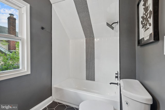 bathroom with baseboards, toilet, shower / bath combination, and tile patterned floors