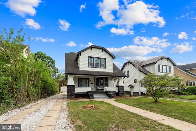 view of front of home featuring a porch, roof with shingles, and a front yard