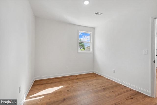 empty room featuring baseboards, light wood-style flooring, and visible vents