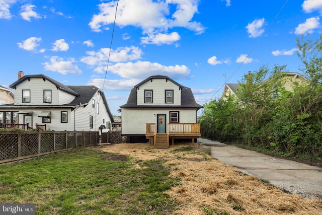 rear view of house featuring a lawn, fence, and a deck