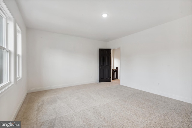 empty room with baseboards, light colored carpet, and plenty of natural light