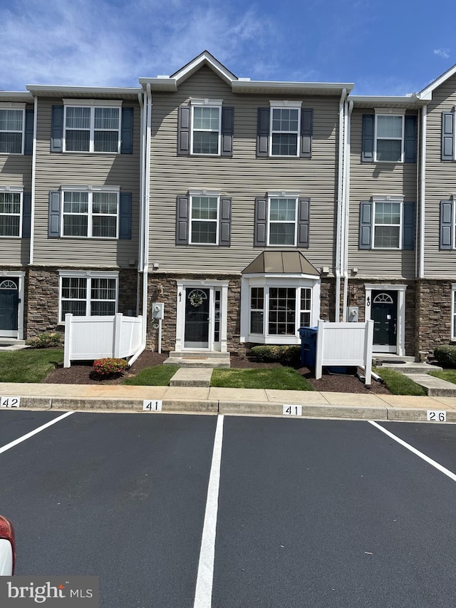 view of property with uncovered parking and stone siding
