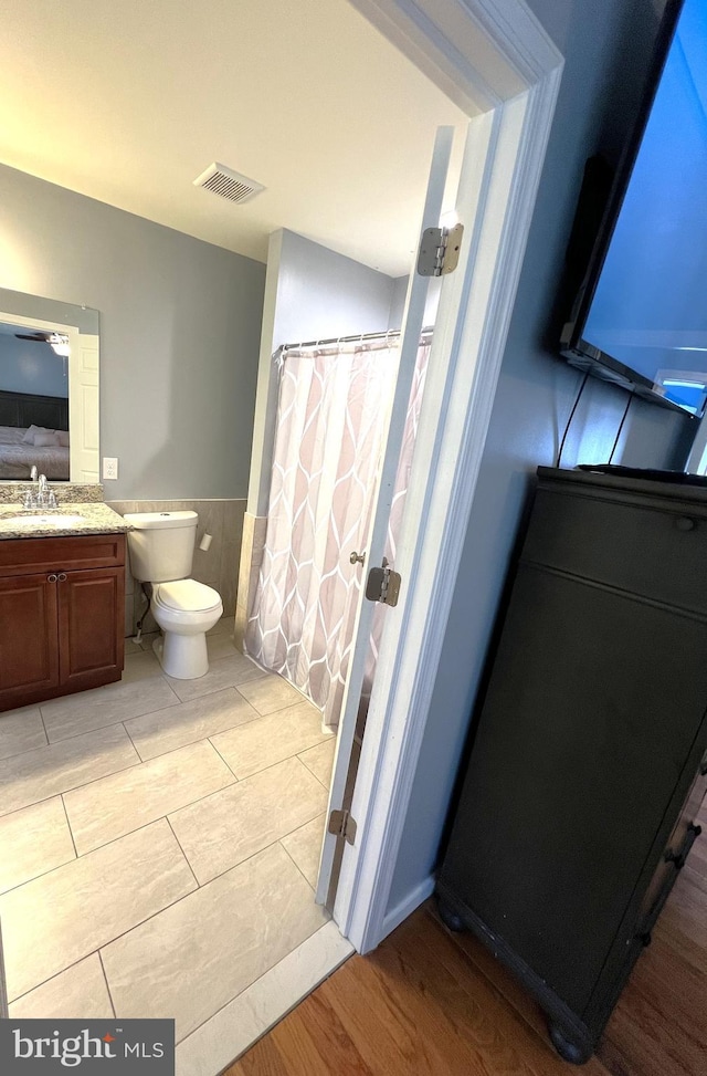 full bathroom with a wainscoted wall, vanity, toilet, and wood finished floors