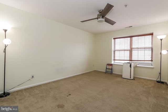 carpeted spare room featuring baseboards, a ceiling fan, and visible vents
