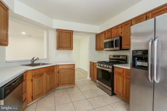 kitchen featuring light countertops, stainless steel appliances, light tile patterned flooring, and a sink