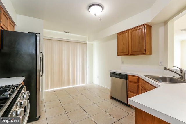 kitchen featuring a sink, appliances with stainless steel finishes, light tile patterned floors, and light countertops