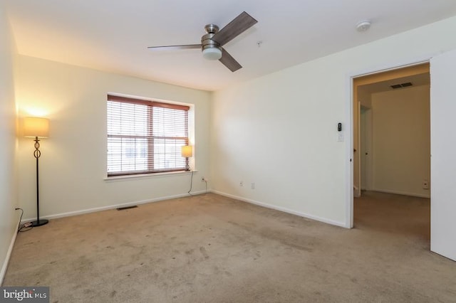 carpeted spare room featuring baseboards, ceiling fan, and visible vents