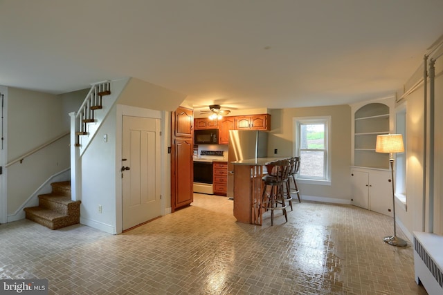 501 Walker Hill Rd, Newport, PA 17074 - kitchen with radiator, black microwave, white electric range, baseboards, and a breakfast bar
