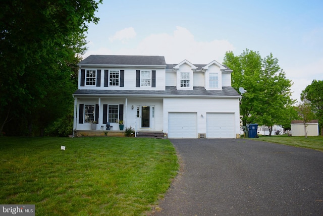 traditional-style house featuring asphalt driveway, covered porch, a garage, and a front lawn