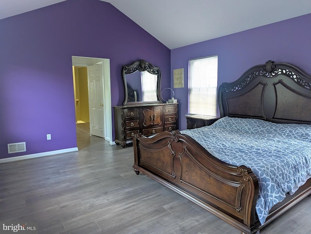 bedroom featuring lofted ceiling, wood finished floors, and baseboards
