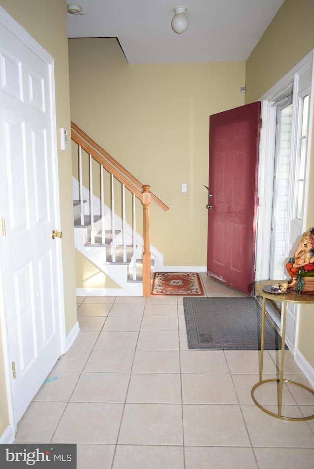 foyer featuring stairway, baseboards, and tile patterned floors