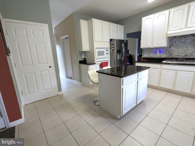 kitchen with appliances with stainless steel finishes, light tile patterned floors, backsplash, white cabinetry, and a center island