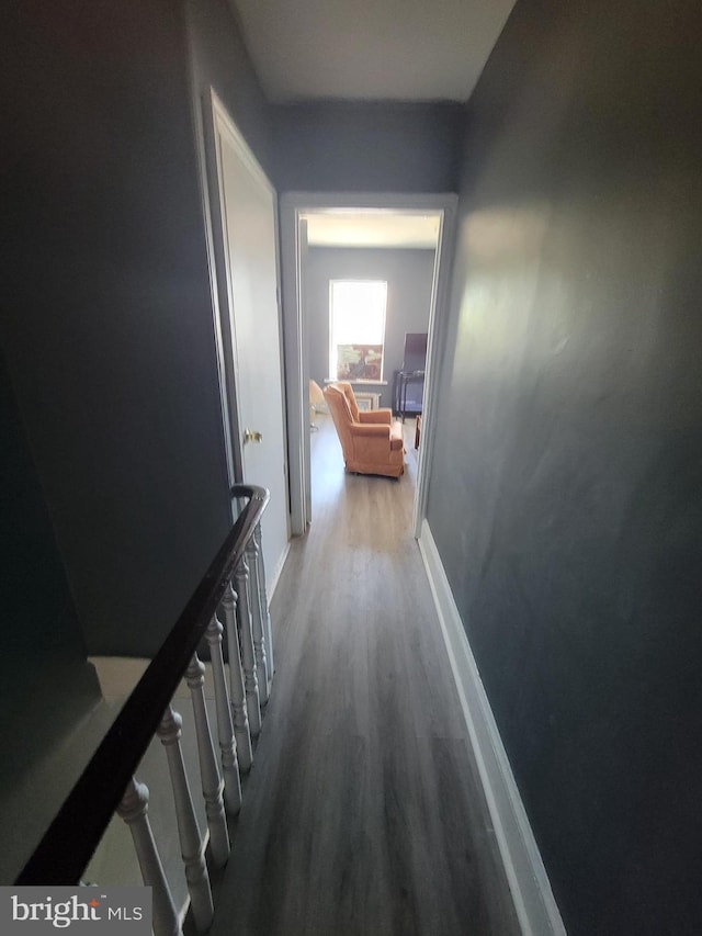 corridor with baseboards and wood finished floors