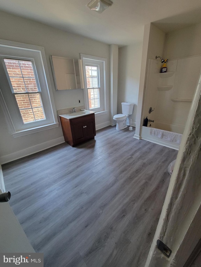 bathroom with vanity, wood finished floors, toilet, baseboards, and shower / bathing tub combination