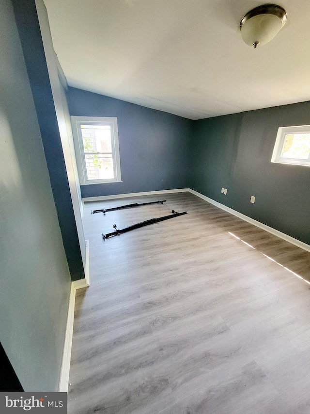 spare room featuring baseboards, plenty of natural light, and vaulted ceiling