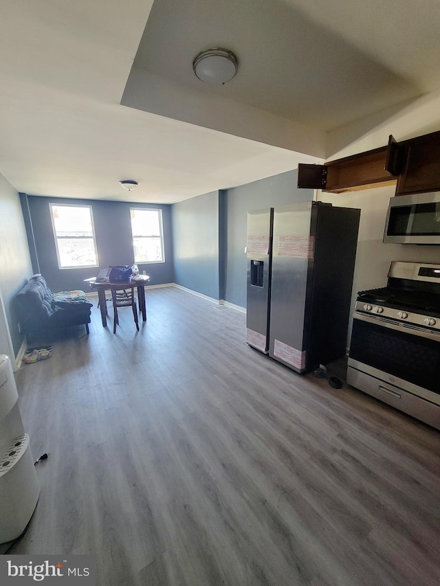kitchen with baseboards, stainless steel appliances, open floor plan, and wood finished floors