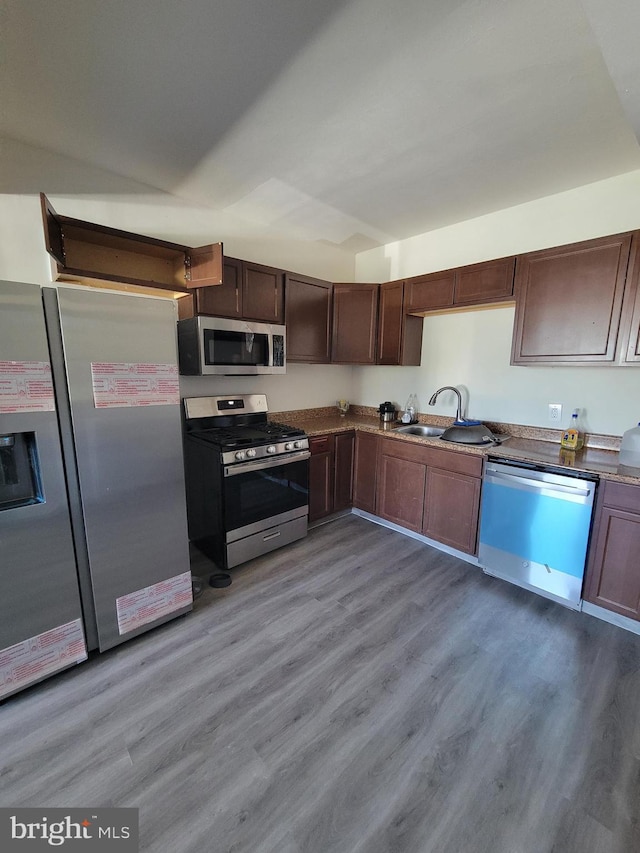 kitchen with stainless steel appliances, a sink, and light wood-style floors