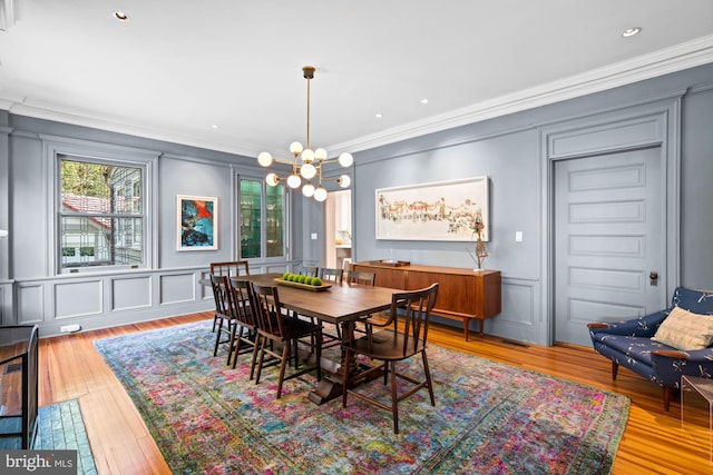 3101 Highland Pl NW, Washington, DC 20008 - dining space featuring crown molding, a decorative wall, hardwood / wood-style flooring, and an inviting chandelier