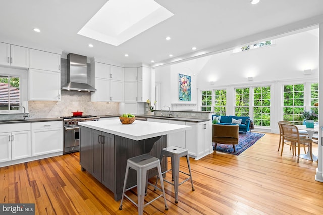3101 Highland Pl NW, Washington, DC 20008 - kitchen featuring wall chimney range hood, a center island, white cabinets, a sink, and high end range