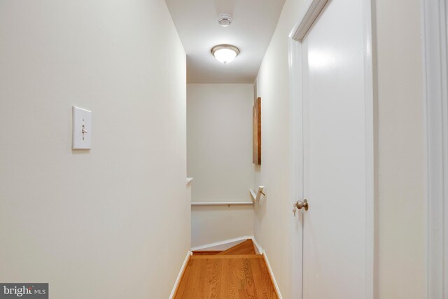 corridor featuring wood finished floors, baseboards, and an upstairs landing