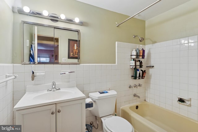 full bathroom featuring tile walls, washtub / shower combination, toilet, and vanity