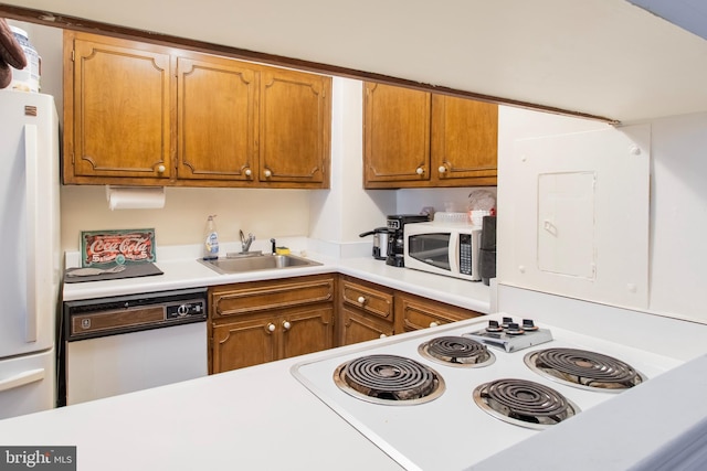 kitchen featuring white appliances, a sink, light countertops, and brown cabinets