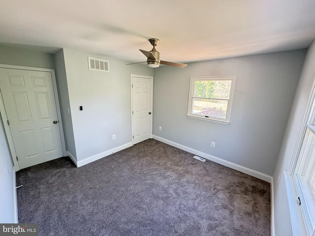 unfurnished bedroom with visible vents, a ceiling fan, baseboards, and dark carpet