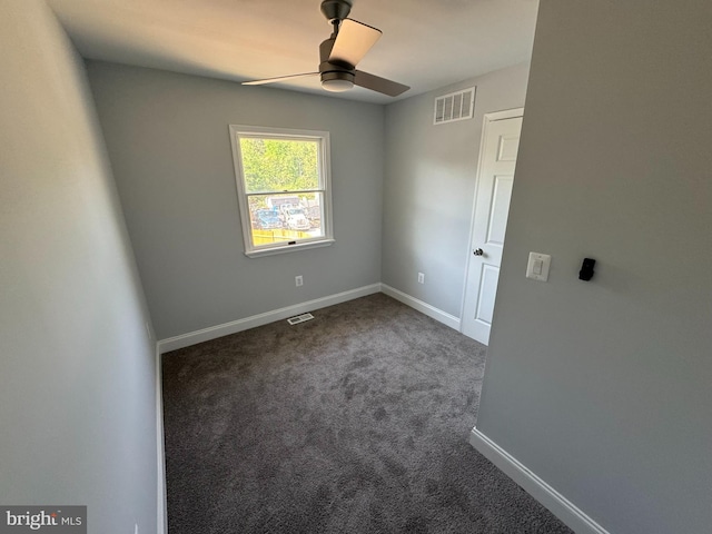 spare room featuring visible vents, baseboards, ceiling fan, and dark colored carpet