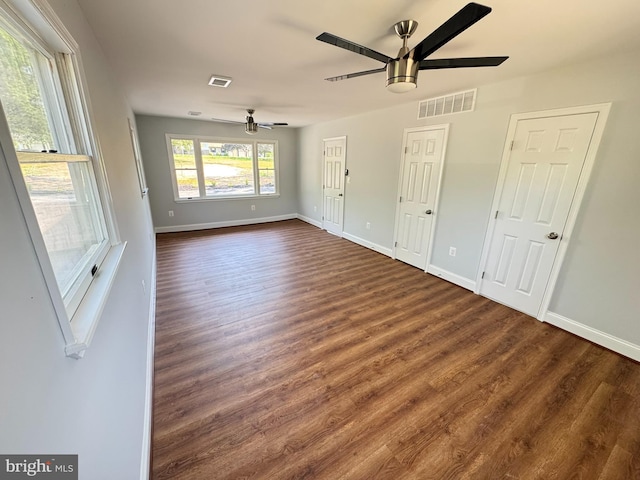 unfurnished living room with ceiling fan, visible vents, and dark wood finished floors