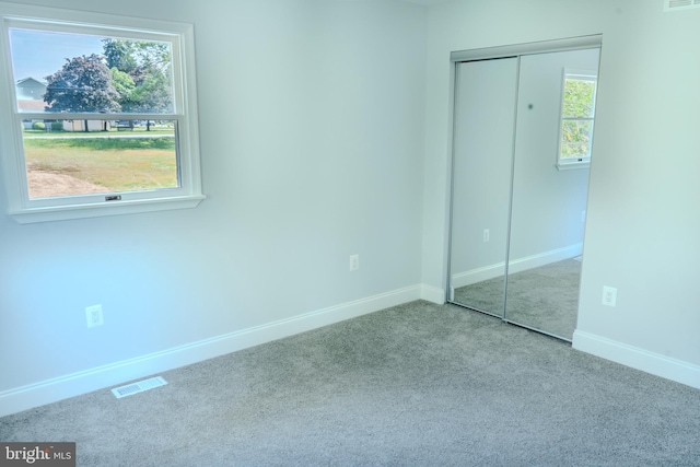 unfurnished bedroom featuring baseboards, carpet, a closet, and visible vents