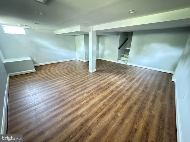 basement with baseboards, stairs, and dark wood-style flooring