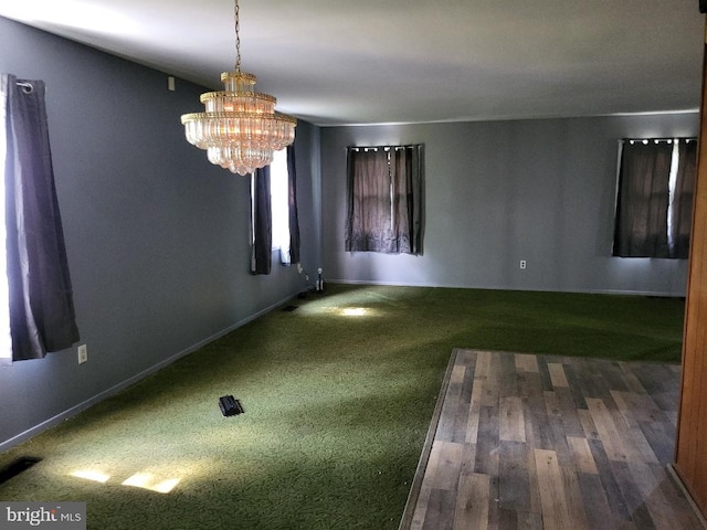 spare room with baseboards, visible vents, and a chandelier