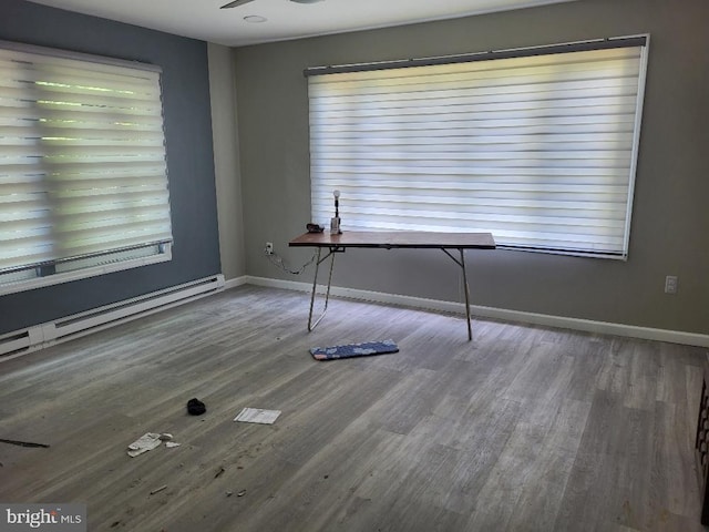 unfurnished dining area featuring baseboards, wood finished floors, and a baseboard radiator