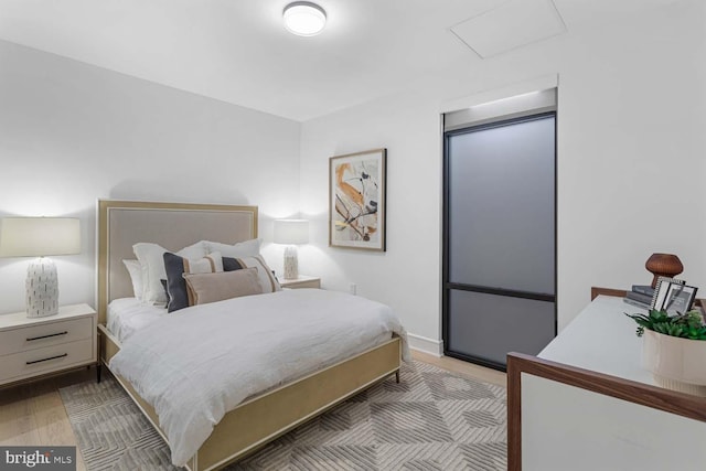 bedroom featuring attic access and wood finished floors