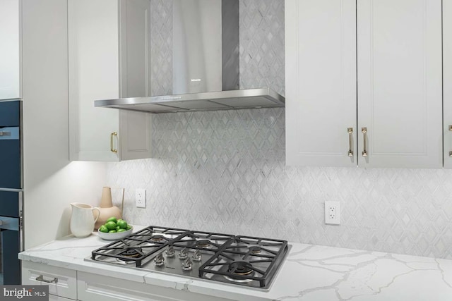kitchen featuring wall chimney range hood, white cabinetry, and stainless steel gas cooktop