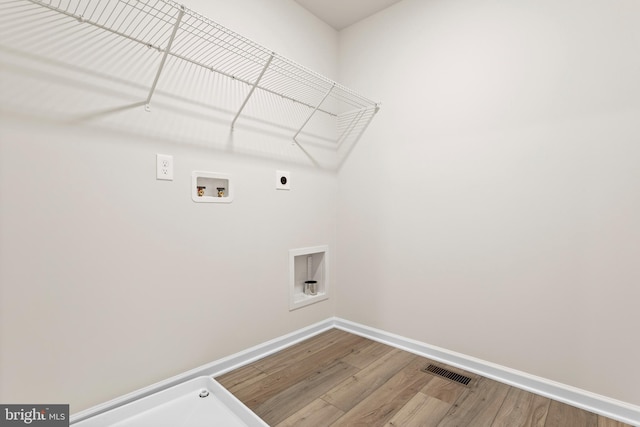 washroom featuring laundry area, visible vents, wood finished floors, baseboards, and hookup for an electric dryer