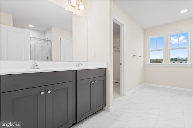 bathroom featuring double vanity, marble finish floor, baseboards, a sink, and a stall shower